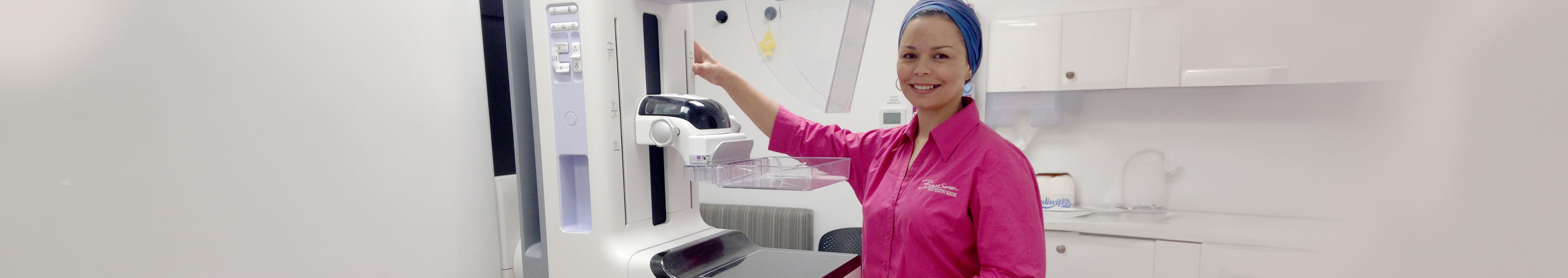 Radiologist smiling and using a mammogram.