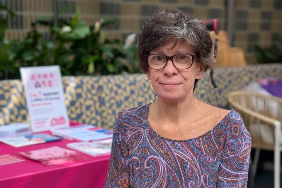 woman with glasses sitting at a table with a pink tablecloth